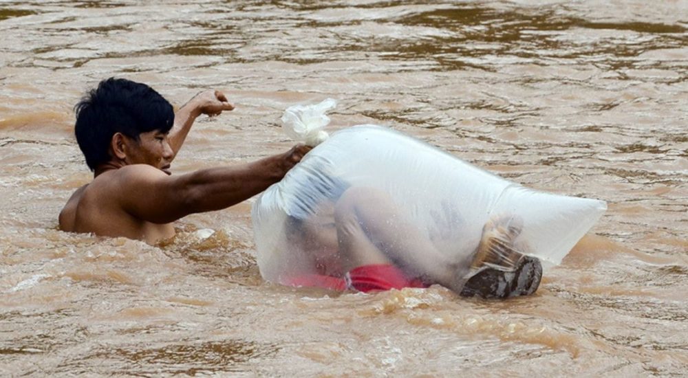 Estudantes são transportados em sacos em rio para não se molharem