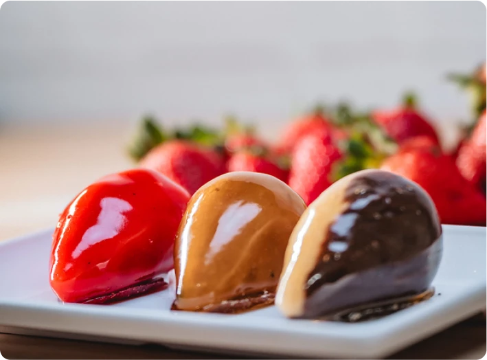 Três versões de morango do amor com coberturas vermelha, caramelada e de chocolate em prato branco